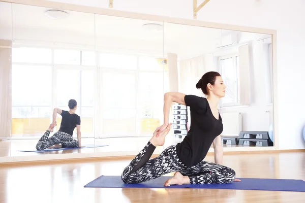 Kvinnan gör yoga på en träningsmatta — Stockfoto