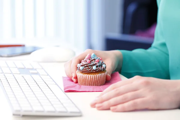 Digitação no teclado do computador com muffin na mão — Fotografia de Stock