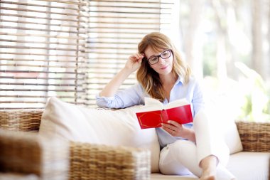 Kadın evde kitap okuyor. 