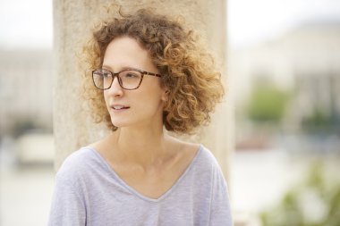 Gözlük ve kıvırcık saçlı olan kadın