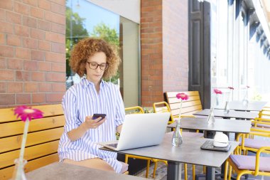 Bir cep telefonu ve dizüstü bilgisayar kullanan kadın