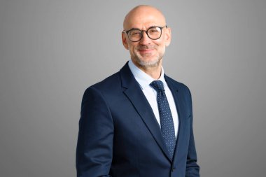 Gri arka planda dikilirken üst düzey yöneticilerin takım elbise giyip kravat taktığı görüntüler. Boşluğu kopyala. 