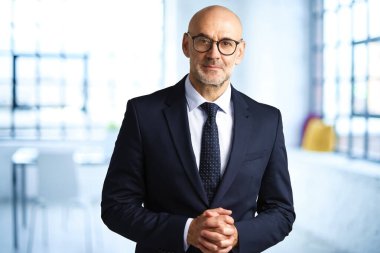 Ofiste dikilirken takım elbise giyip kravat takan kendinden emin iş adamının portresi..