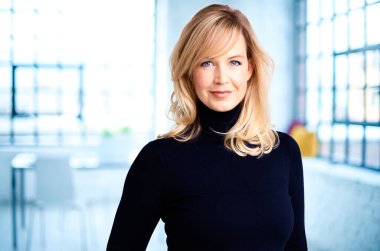 Güzel sarı saçlı iş kadınının portre resmi. Kameraya bakıyor ve ofiste dururken gülümsüyor.. 