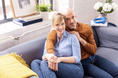 Mutlu çiftin evdeki kanepede oturup evde dinlenirken birbirleriyle bağ kurmaları..