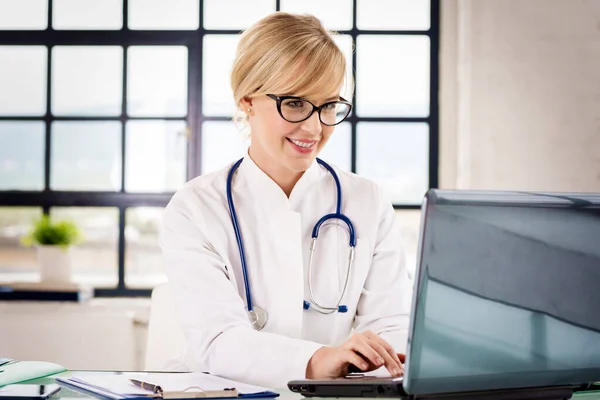 Tiro Doctora Sonriente Trabajando Portátil Mientras Está Sentada Escritorio Oficina — Foto de Stock