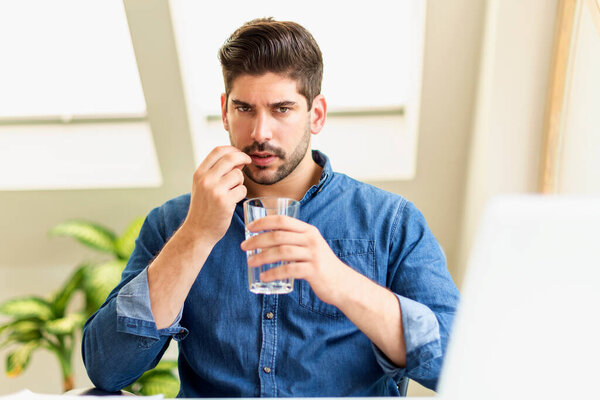 Застрелен бизнесмен с таблеткой в руке испытывает стресс во время сидения за ноутбуком и страдает от сильной головной боли. 