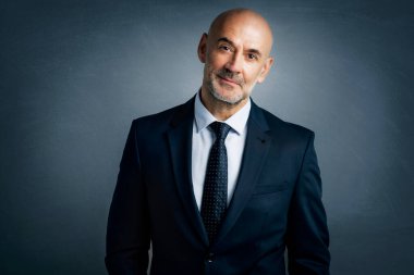 Orta yaşlı iş adamının izole edilmiş arka planda dikilirken takım elbise giyip kravat taktığı bir resim. Boşluğu kopyala. 