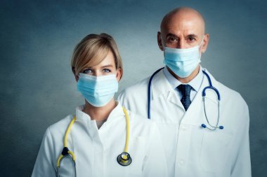 İzole bir arka planda kadın ve erkek doktorların bir arada durduğu bir sahne. Tıbbi ekip. Önlem için yüz maskesi takan doktorlar.