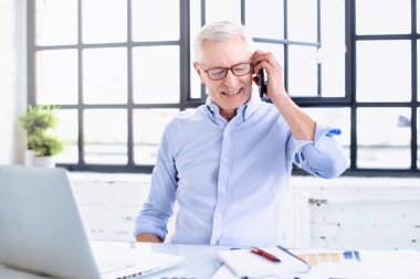 Üst düzey bir iş adamının, defterinin arkasında oturup ofiste çalışırken telefon görüşmesi yaparken görüntüsü.. 