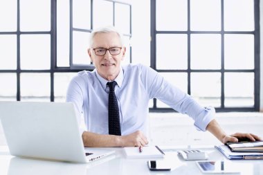 Ofiste çalışırken üst düzey bir iş adamının dizüstü bilgisayarının başında oturması.. 