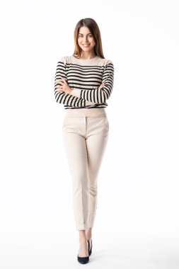 Stüdyoda, günlük giysiler içinde mutlu genç bir kadının izole edilmiş beyaz arka planda durup gülerken çekilmiş bir fotoğrafı.. 