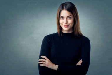 Gri arka planda duran güzel kahverengi saçlı kadının stüdyo portresi..