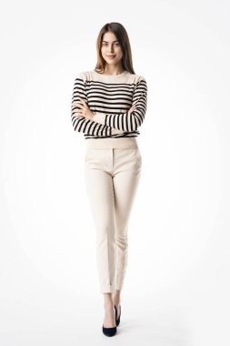 Güzel bir genç kadının, izole edilmiş beyaz arka planda dikilirken günlük kıyafetler giydiği uzun bir stüdyo fotoğrafı.. 