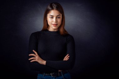 Koyu gri arka planda duran güzel kahverengi saçlı kadının stüdyo portresi. Boşluğu kopyala.