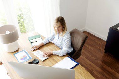 Finans asistanı iş kadınının ofis masasında oturup bilgisayar başında çalışmasının yukarıdaki çekimlerinden. Merkez Ofis.