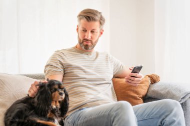 Kanepede köpek yavrusu ve mesajlarıyla oturan yakışıklı adamın fotoğrafı.. 
