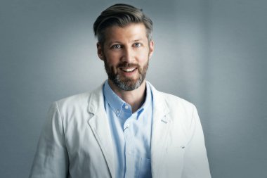 Gri arka planda dikilirken spor ceket ve gömlek giyen orta yaşlı yakışıklı işadamının portresi. Boşluğu kopyala.