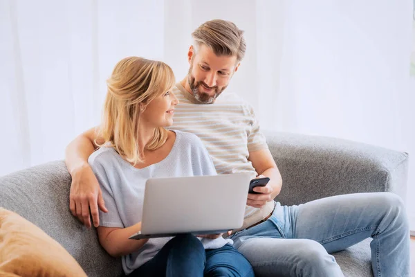 Shot Pareja Encantadora Relajarse Sofá Casa Uso Ordenador Portátil Teléfono —  Fotos de Stock