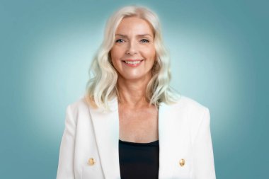 Stüdyo resmi, sarı saçlı yaşlı bir kadının izole arka planda dururken kameraya bakıp gülümsemesi. Boşluğu kopyala.