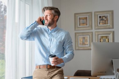 Kahve molasındayken ofis masasında iş görüşmesi yapan yakışıklı iş adamı..