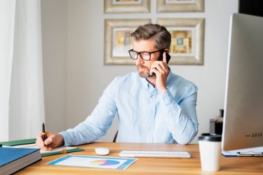 İşadamı bilgisayarının arkasında oturuyor ve bir telefon görüşmesi yapıyor. Merkez Ofis.