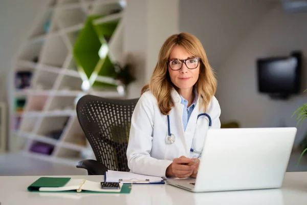 Glimlachende Vrouwelijke Arts Zit Aan Het Bureau Werkt Aan Laptop — Stockfoto