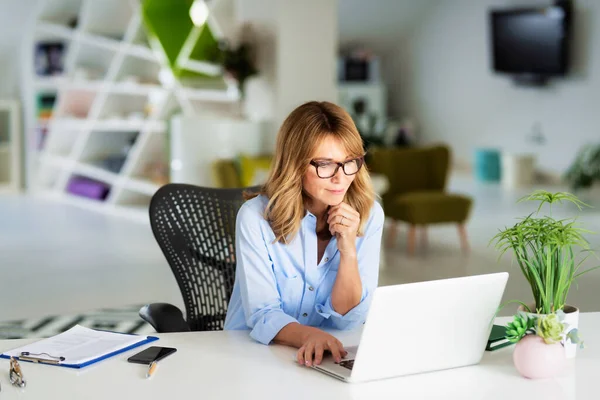 Sorrindo Empresária Meia Idade Trabalhando Laptop Enquanto Sentado Mesa Escritório — Fotografia de Stock