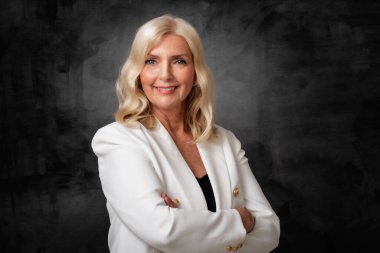 Stüdyo portresi gülen gri saçlı yaşlı kadın izole edilmiş koyu arka planda duruyor. Boşluğu kopyala. 