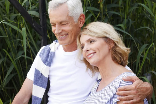 Happy senior couple sitting at the lakeside — Stock Photo, Image