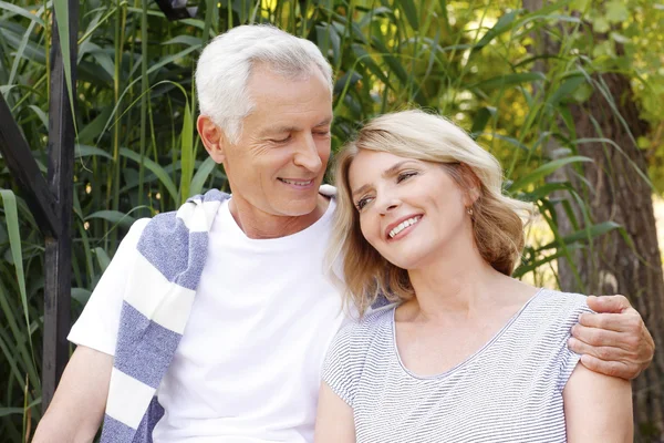 Feliz pareja de ancianos sentados a orillas del lago — Foto de Stock