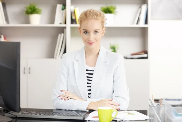 Ofiste oturan genç iş kadını — Stok fotoğraf