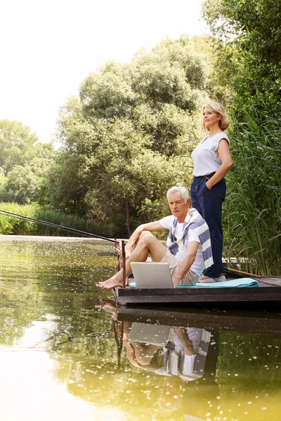 Senior couple chilling out at lake shore — 图库照片