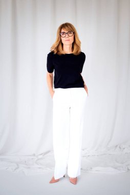 Sarışın kadın, izole edilmiş arka planda duruyor ve kameraya bakıyor. Orta yaşlı kadın iş kıyafeti giyiyor. Uzayı kopyala Tam uzunluk. 