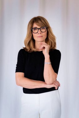 Sarışın kadın, izole edilmiş arka planda duruyor ve kameraya bakıyor. Orta yaşlı kadın iş kıyafeti giyiyor. Boşluğu kopyala. 