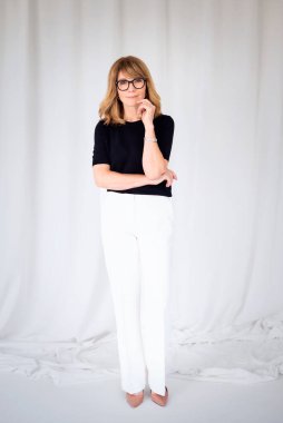 Sarışın kadın, izole edilmiş arka planda duruyor ve kameraya bakıyor. Orta yaşlı kadın iş kıyafeti giyiyor. Uzayı kopyala Tam uzunluk. 