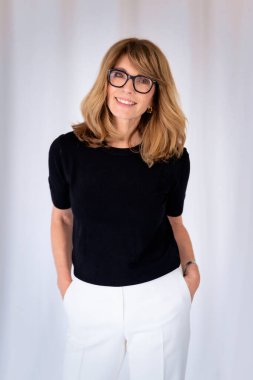 Sarışın kadın, izole edilmiş arka planda duruyor ve kameraya bakıyor. Orta yaşlı kadın iş kıyafeti giyiyor. Boşluğu kopyala. 