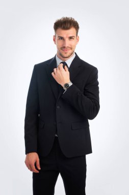 Takım elbiseli ve kravatını düzelten genç bir adamın Studi çekimi. Özgüvenli erkek izole edilmiş arka plana karşı duruyor ve kameraya gülümsüyor. Boşluğu kopyala. 