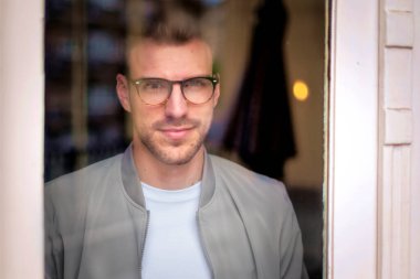 Modern ofisin penceresinin yanında duran kendinden emin genç işadamının portresi. 