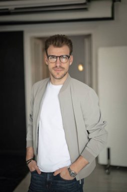 Kameraya bakıp gülümseyen genç bir adamın vesikalığı. Beyaz gömlek ve ceket giyen ve içeride duran kendine güvenen bir adam.. 