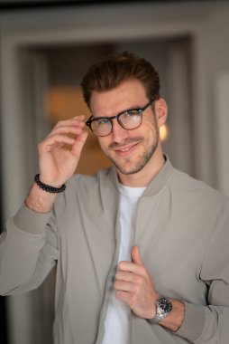 Kameraya bakıp gülümseyen genç bir adamın vesikalığı. Beyaz gömlek ve ceket giyen ve içeride duran kendine güvenen bir adam.. 