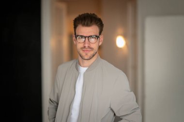 Kameraya bakıp gülümseyen genç bir adamın vesikalığı. Beyaz gömlek ve ceket giyen ve içeride duran kendine güvenen bir adam.. 