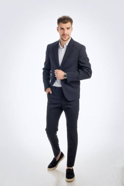 İş kıyafeti giymiş sakallı bir gencin portresi ve izole edilmiş beyaz arka plana karşı ayakta duruyor. Stüdyo çekimi, kopyalama alanı. Tam uzunluk.