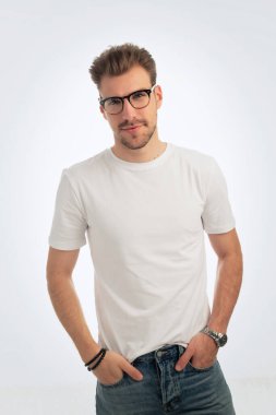 Sıradan kıyafetler giyen ve izole edilmiş beyaz arka planda duran sakallı bir gencin portresi. Beyaz gömlek ve kot pantolon. Stüdyo çekimi, kopyalama alanı. Yakın çekim..