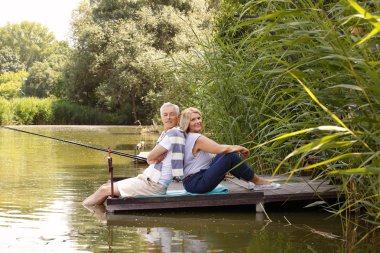 Smiling senior people sitting on pier