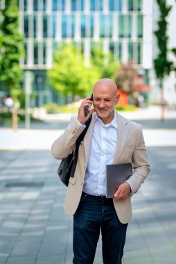 Şehirde iş bölgesinde yürüyen yakışıklı bir adam. Orta yaşlı işadamı iş kıyafeti giyiyor ve telefon görüşmesi yapıyor..