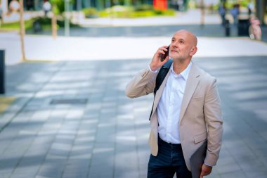 Şehirde iş bölgesinde yürüyen yakışıklı bir adam. Orta yaşlı işadamı iş kıyafeti giyiyor ve telefon görüşmesi yapıyor..