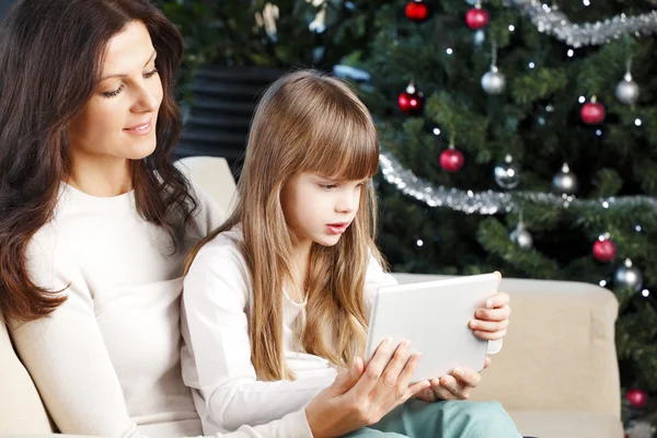 Madre e hija sentadas en el árbol de Navidad —  Fotos de Stock
