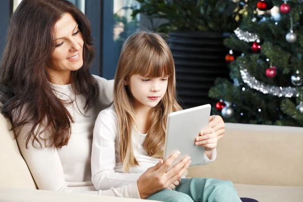 Madre e hija sentadas en el árbol de Navidad —  Fotos de Stock