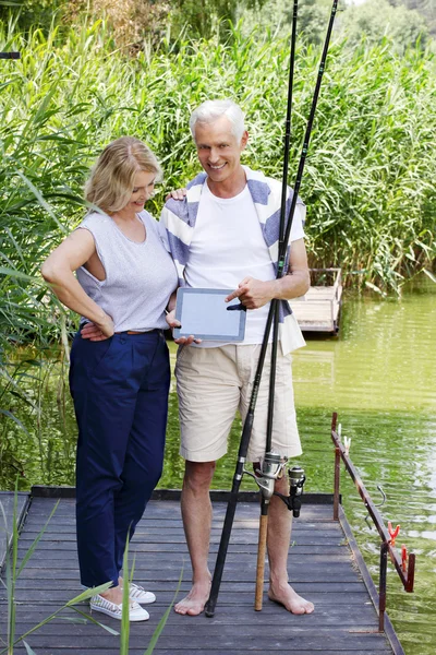 Lyckliga äldre par med digital tablet — Stockfoto